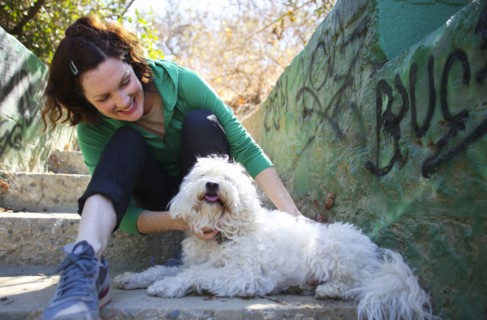 Caucasian woman petting dog on staircase with graffiti