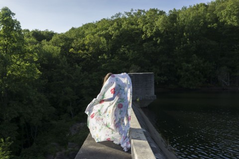Woman playing with fabric on stone bridge