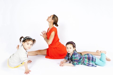 Mother practicing yoga with playful daughters
