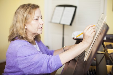 Caucasian musician writing sheet music at piano