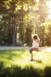 Girl sitting on swing in field