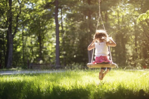 Girl sitting on swing in field