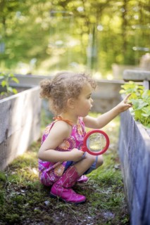 Girl examining garden plants with magnifying glass