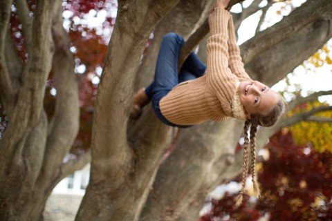 Low angle view of smiling girl climbing tree
