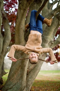 Smiling girl hanging upside-down in tree