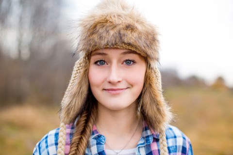Caucasian teenage girl wearing fur hat in field