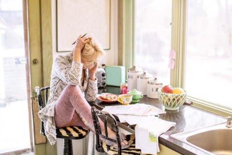 Caucasian woman paying bills on telephone in kitchen