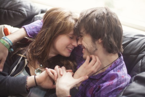 Caucasian couple holding hands on sofa