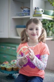 Caucasian girl licking mixing paddle in kitchen
