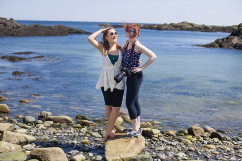Smiling women standing on rocky beach