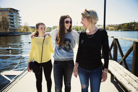 Mother and daughters walking on dock in harbor
