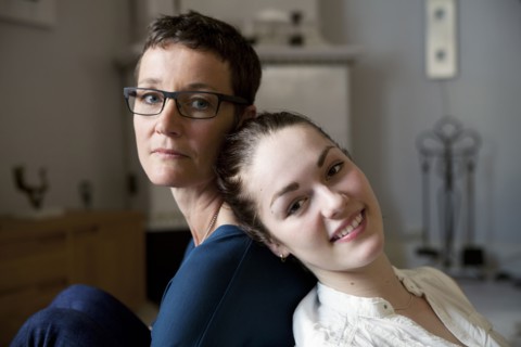 Caucasian mother and daughter sitting back to back