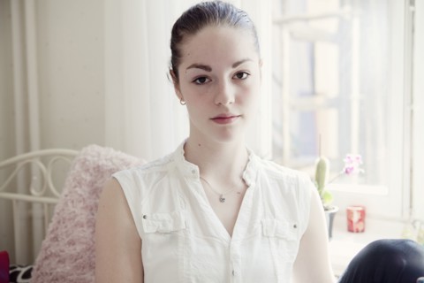 Caucasian teenage girl sitting on bed