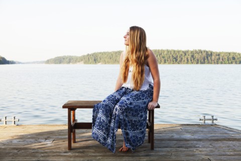 Caucasian teenage girl sitting on wooden dock at lake
