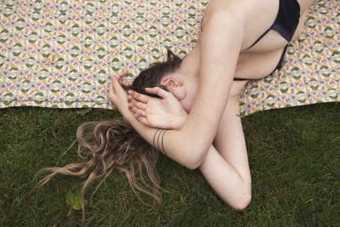 Woman sunbathing in bikini on blanket in grass