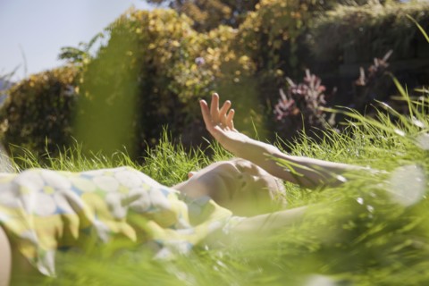 Woman laying in tall grass in park