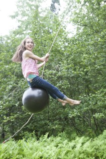 Teenage girl swinging on rope swing