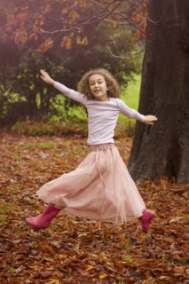 Caucasian girl jumping for joy in autumn leaves