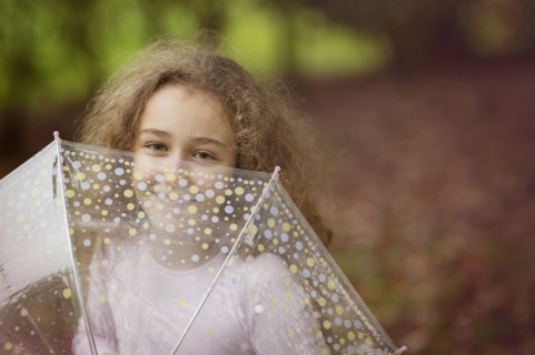 Caucasian girl playing with umbrella outdoors