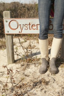 Woman wearing boots near sign on beach