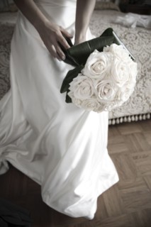 Bride with bouquet sitting on bed