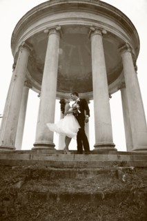 Caucasian bride and groom hugging under columns
