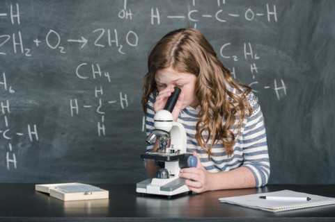 Caucasian student using microscope in science class