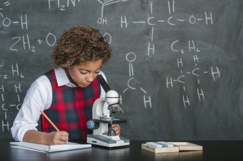 Mixed race student using microscope in science class