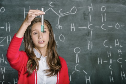 Hispanic student examining test tube in science class