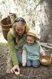 Mother and son foraging for mushrooms in forest