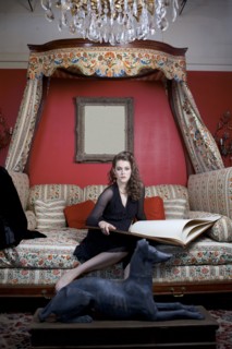 Woman reading oversized book on sofa in ornate living room
