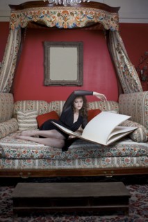 Woman reading oversized book on sofa in ornate living room