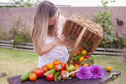 Mixed race woman with basket of vegetables and flowers