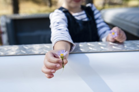 Caucasian girl holding flowers in truck bed