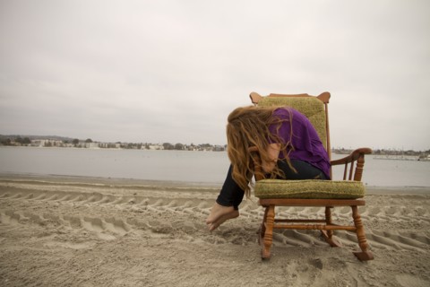 Woman sitting in armchair on beach