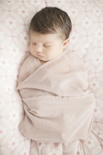 Caucasian baby girl swaddled in blanket