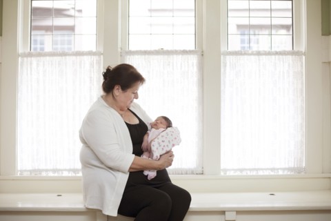 Caucasian woman holding baby granddaughter in windowsill