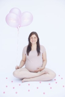 Pregnant Caucasian woman holding bunch of balloons