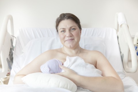 Caucasian mother nursing newborn daughter in hospital bed