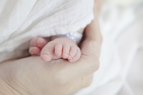 Caucasian mother holding foot of newborn daughter