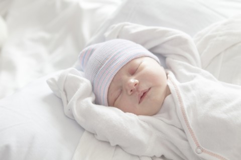 Caucasian newborn girl laying on bed