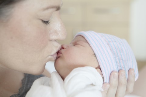 Caucasian mother kissing newborn daughter