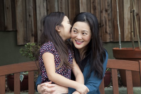Mother and daughter whispering secrets in backyard