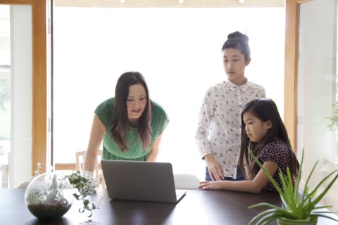 Mother and daughters using laptop in dining room