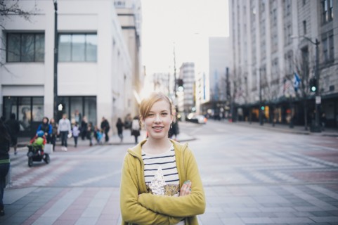 Teenage girl standing with arms crossed in city intersection