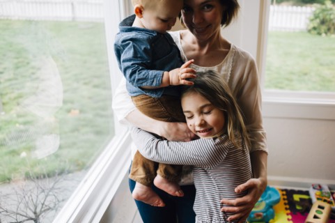 Mother and children hugging at window