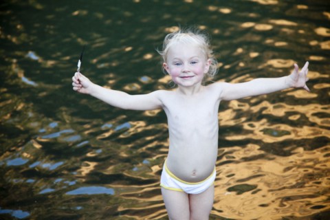 Smiling girl standing with arms outstretched at lake