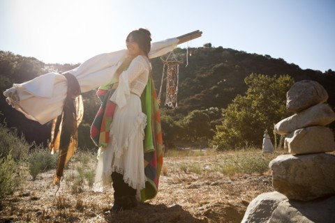 Hispanic woman carrying teepee in desert