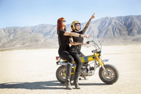 Women sitting on motorcycle in desert