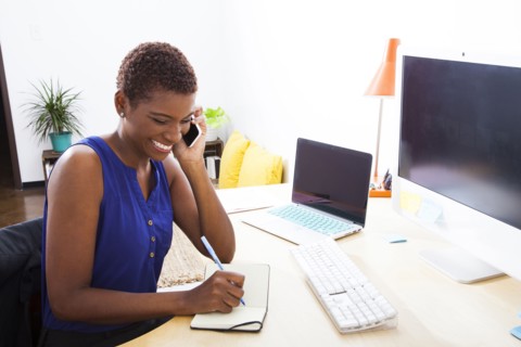 Black businesswoman talking on cell phone at office desk